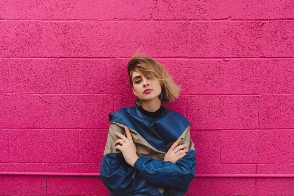 pretty girl against pink wall with arms folded