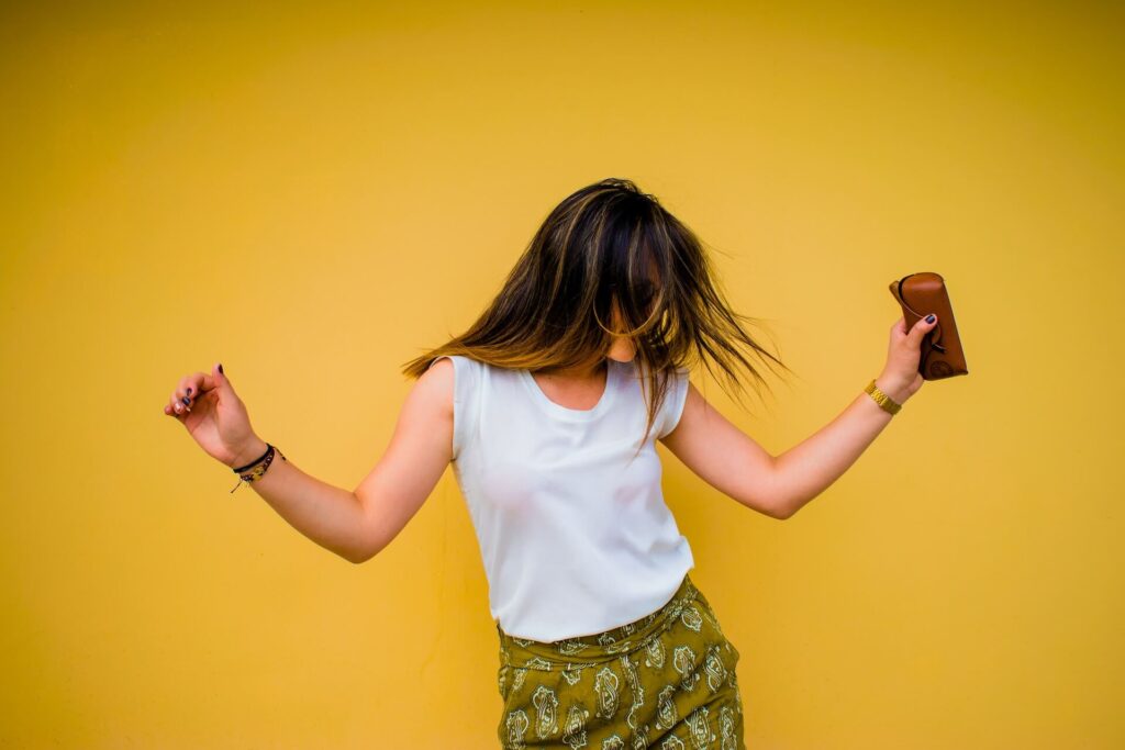 girl dancing and listening to spanish music against a yellow wall